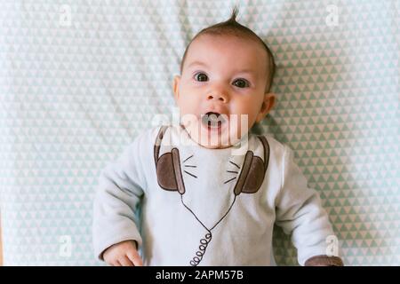 Portrait of surprised baby girl with appliqued headphones on pyjama Stock Photo