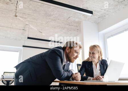 Businessman and businesswoman using laptop in office Stock Photo