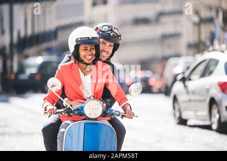 Happy young business couple riding motor scooter in the city, Lisbon, Portugal Stock Photo