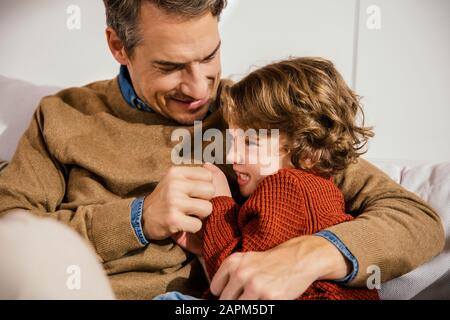 Father playfighting with daughter on couch Stock Photo