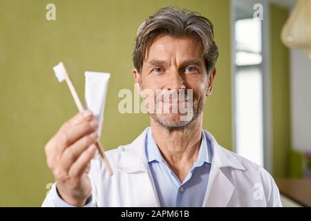 Portrait of dentist holding toothbrush and toothpaste in his medical practice Stock Photo
