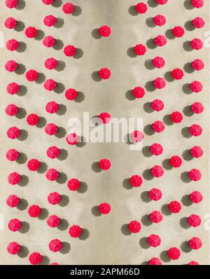 Aerial view of arrangement of red beach umbrellas on sandy beach Stock Photo