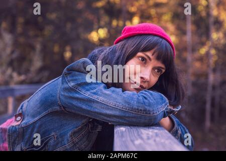 Woman wearing red woolly hat and denim jacket looking sideways Stock Photo