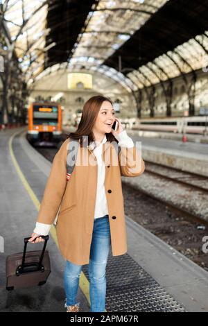 Young woman talking on the phone at the train station Stock Photo