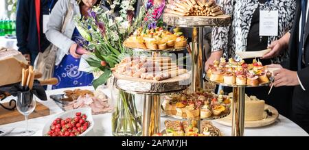 Businesspeople at banquet lunch break at business conference meeting. Assortment of canapes and finger food on the table. Stock Photo