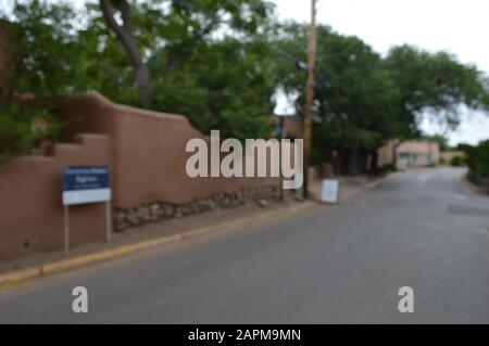 A quiet residential street in Santa Fe, New Mexico, with adobe-style homes, gravel driveways, stone walls, native desert landscaping, and Southwestern Stock Photo
