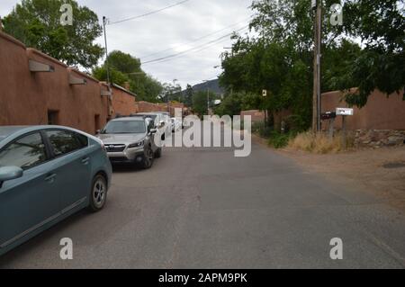 A quiet residential street in Santa Fe, New Mexico, with adobe-style homes, gravel driveways, stone walls, native desert landscaping, and Southwestern Stock Photo