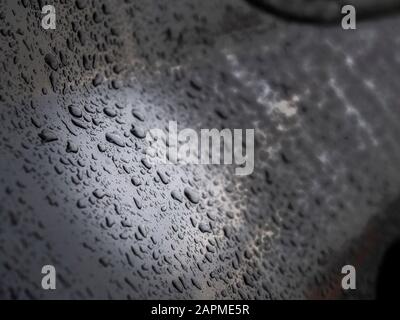 Close up of water drops on dark gray car after rain. Stock Photo