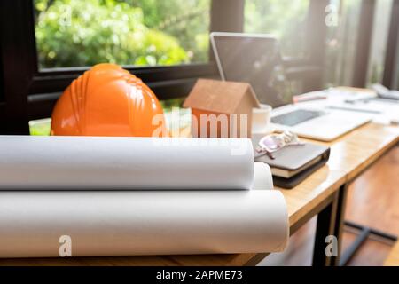 Blueprint with helmet and architects house model on desk. Stock Photo