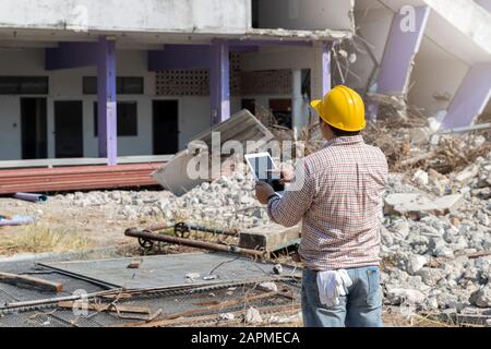 Engineer holding tablet is checking for destruction, demolishing building. Stock Photo