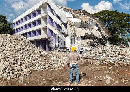 Engineer holding tablet is checking for destruction, demolishing building. Stock Photo