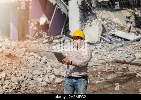 Engineer holding tablet is checking for destruction, demolishing building. Stock Photo