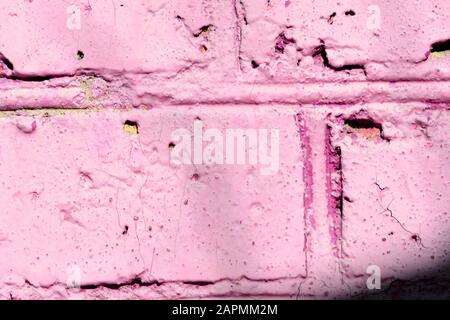 Fragment of an old brick wall painted pink paint with a shadow from tree branches on a sunny day. Abstract background Stock Photo