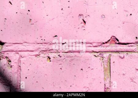 Fragment of an old brick wall painted pink paint with a shadow from tree branches on a sunny day. Abstract background Stock Photo