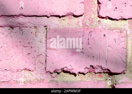 Fragment of an old brick wall painted pink paint with a shadow from tree branches on a sunny day. Abstract background Stock Photo