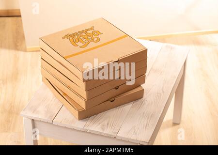 Stack of pizza boxes on wooden table. Food delivery to office. Stock Photo