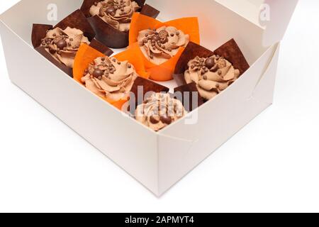 open box of chocolate cupcakes with cream top and crispy topping in paper on a white background Stock Photo