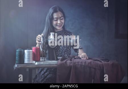 Woman using vintage sewing machine. adorable elderly woman sewing clothes Stock Photo