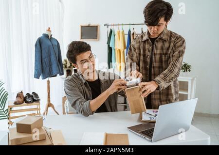 young asian people businessman chatting about packaging of camera lens at work Stock Photo