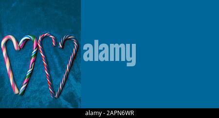 Holiday candy canes heart on trendy blue background with copy space Stock Photo