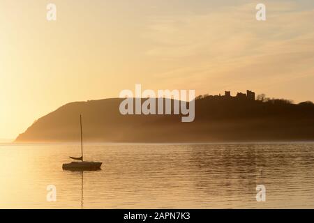 Atmospheric misty evening light sunset over Llansteffan Castle from Ferryside Carmarthenshire Wales Cymru UK Stock Photo