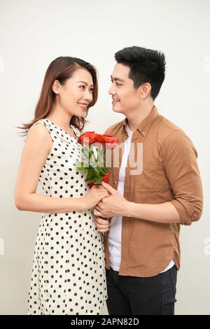 All my love for you. Close-up portrait of beautiful young couple holding bouquet of roses and smiling while looking on each other while isolated on wh Stock Photo