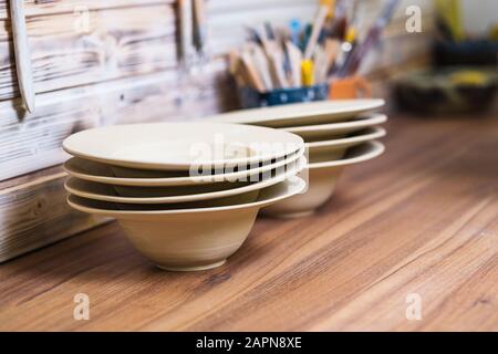 Hand made plates, bawls and tools on pottery studio table, shallow debt of field, small art business concept Stock Photo