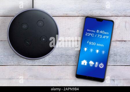 Smart home automation by Alexa Echo Plus controlled with a smart phone app on a white wooden table. Empty copy space for Editor's text. Stock Photo
