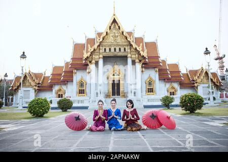 Woman tourist with red traditional Thai umbrella at Wat Benchamabophit the marble temple in Bangkok, Thailand Stock Photo