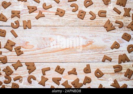 A lot of letter shape cookies on wooden table. Text empty space in the center Stock Photo
