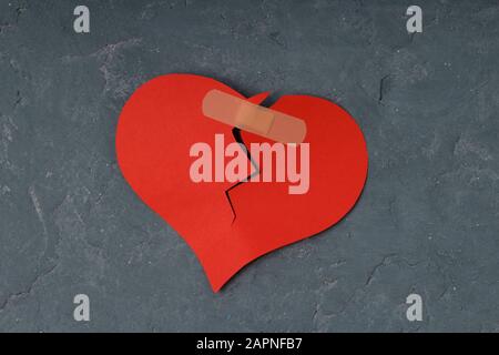 Broken heart and glued together with a band-aid. concrete background Stock Photo