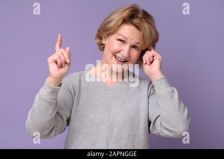 Funny middle age mature woman pointing with finger up giving advice. Grandmother making a smart decision. Stock Photo