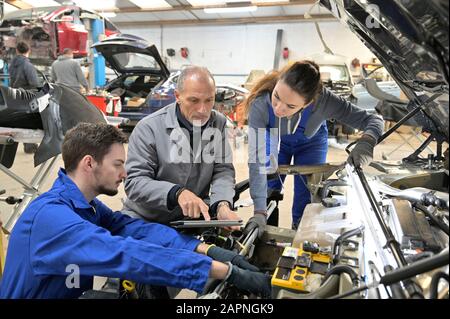 Instructor with trainees working on car engine Stock Photo