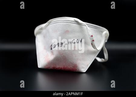Blood-stained safety mask after a 2019-nCOV coronavirus infection isolated on a black background. Stock Photo
