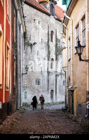 Two women walking down cobbled lane between medieval houses / buildings on a winter's day. Vanalinn, Tallinn, Estonia Stock Photo