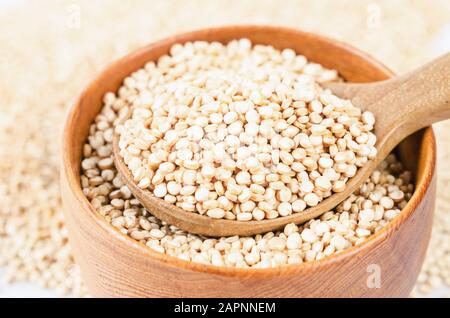 quinoa seeds in wooden spoon on white background. Stock Photo