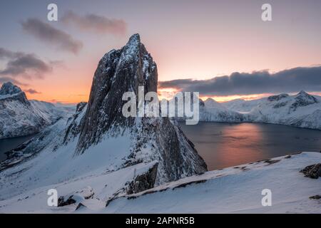 View from Mount Hesten on Iconic Mountain Segla at dawn in winter with colorful sky and mountain range in background, Fjordgard, Senja, Norway