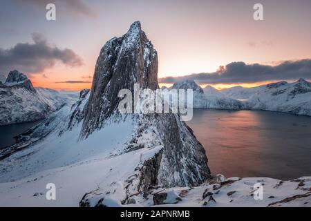 View from Mount Hesten on Iconic Mountain Segla at dawn in winter with colorful sky and mountain range in background, Fjordgard, Senja, Norway