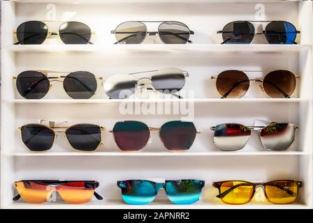 Sunglasses of different colors on the store white counter. beautiful and bright, selection and assortment. Stock Photo