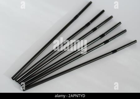 Six tubules for cocktails on a light background. Black drinking straws on the table. Close-up. Selective focus. Stock Photo