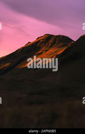 Beautiful scenic sunset in Iceland. Yellow lit mountain side with pink clouds. September 2018 Stock Photo