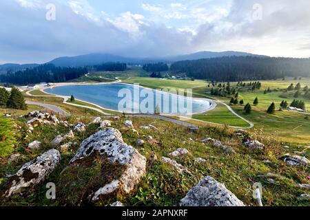 The lake and meadows at the Coe pass: Base Tuono museum on the right, Mount Maggio in the background. Folgaria, Cimbra Alp, Trentino, Italy. Stock Photo