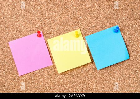 Blank sticky notes pinned on cork memo board. Stock Photo