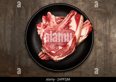Two steaks in a black plate on a rusty metal table Stock Photo