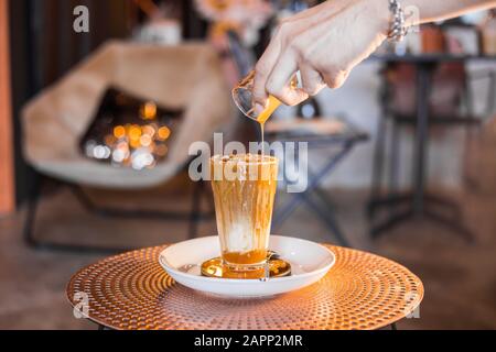 Iced coffee with milk in tall glasses on the table with caramel syrup poured on top. Stock Photo