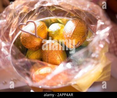 Easter eggs in an opened pink cellophane wrapping. A heart motif decorates the basket. Stock Photo