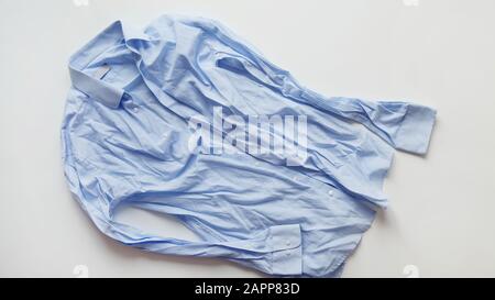 Blue cotton wrinkled and rumpled shirt on white. Washed shirt after tumble dryer. Stock Photo