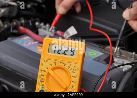 Battery voltage measurement with a meter. Car repair shop. Stock Photo