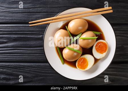 Nitamago ramen boiled eggs in soya marinade with green onions close-up in a plate on the table. Horizontal top view from above Stock Photo