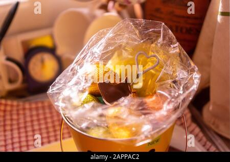 Easter eggs in an opened pink cellophane wrapping. A heart motif decorates the basket. Stock Photo